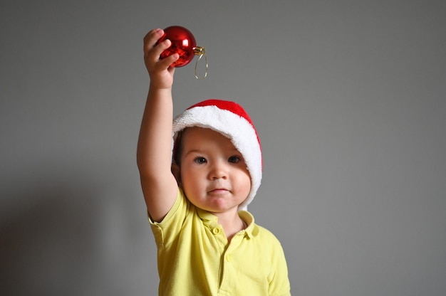 Niño sosteniendo una pelota en un sombrero de Navidad. Foto de alta calidad