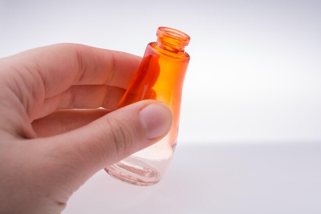 Niño sosteniendo una pequeña botella de vidrio vacía y colorida sobre un fondo blanco