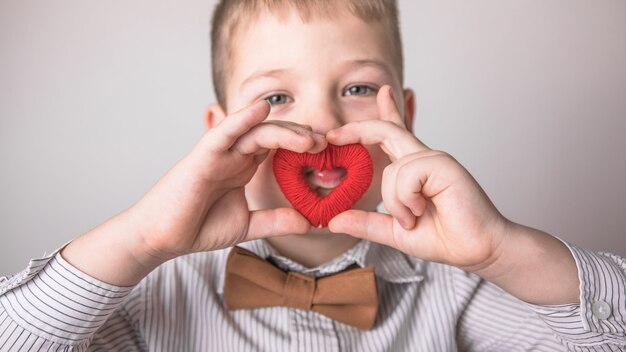 Niño sosteniendo un pequeño corazón rojo