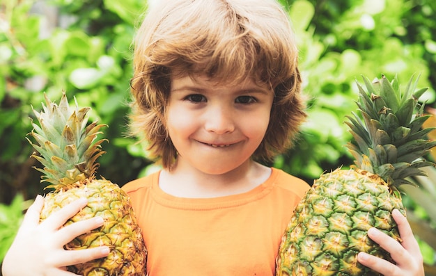 Niño sosteniendo piña y niños sonrientes con piña