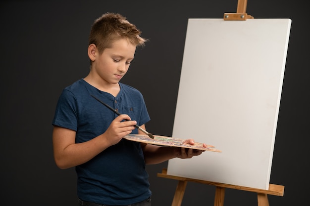 Niño sosteniendo un pincel y paleta con pinturas