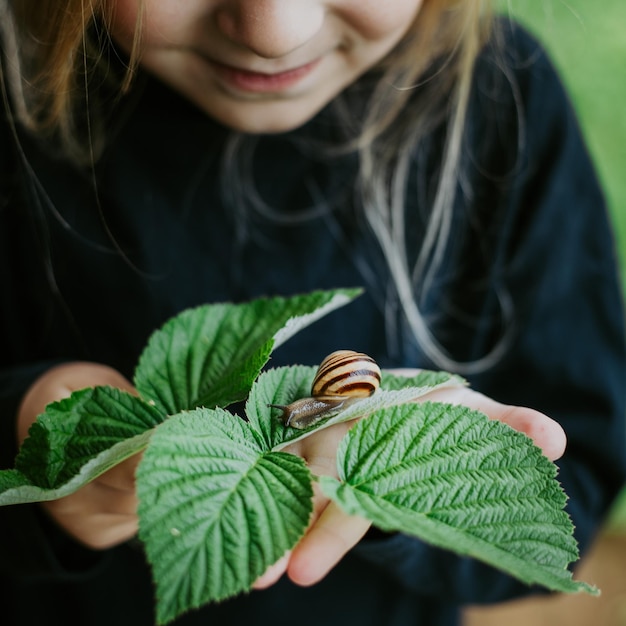 Foto niño sosteniendo rama con caracol