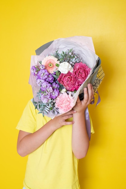 Foto el niño sostiene un arreglo floral en una caja redonda. un regalo para mamá