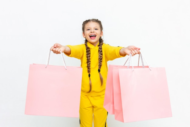 El niño sostiene las bolsas con las dos manos Hermosa niña después de ir de compras con bolsas de papel