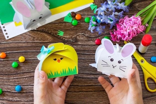 Niño sostiene una caja para empacar dulces con conejito de Pascua y pollito de Pascua