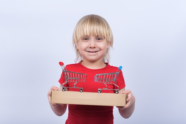 Niño sostiene en la caja de manos y dos carrito de compras