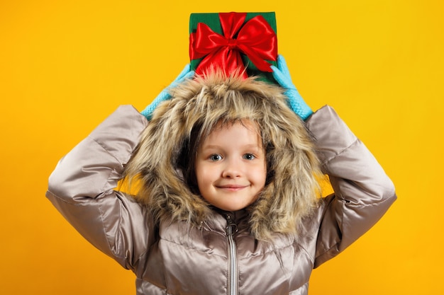 El niño sostiene una caja con un regalo en la cabeza.