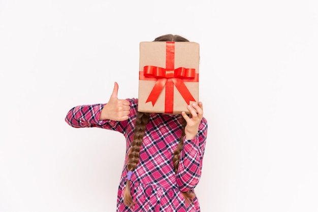 El niño sostiene una caja de regalo en lugar de una cabeza y da un pulgar hacia arriba El concepto de vacaciones Fondo blanco aislado