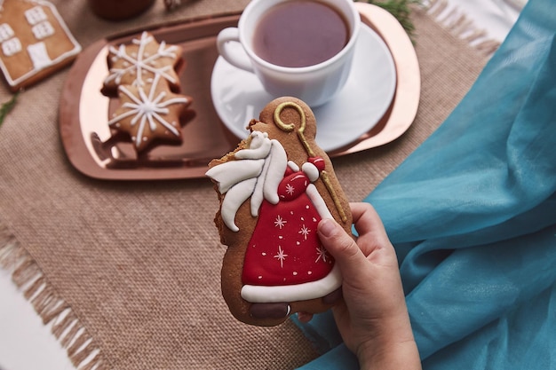 Niño sostiene galletas de jengibre de Navidad mordidas de San Nicolás cerca del cacao Decoraciones navideñas de temporada en un hogar acogedor Vacaciones tradicionales en Europa