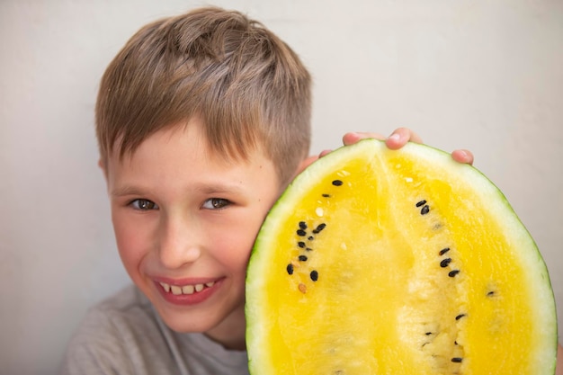 El niño sostiene una gran sandía amarillaNiño con fruta