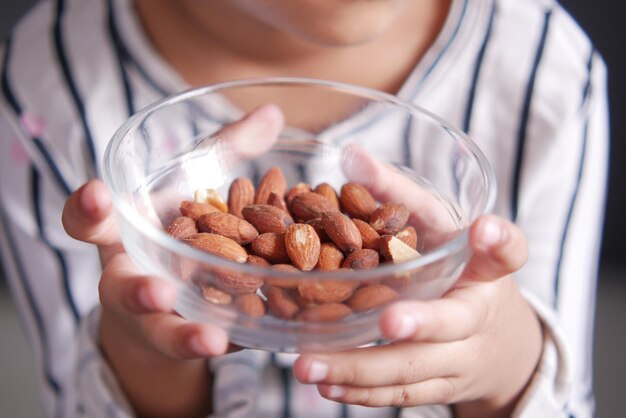 Foto el niño sostiene con la mano un cuenco de almendras