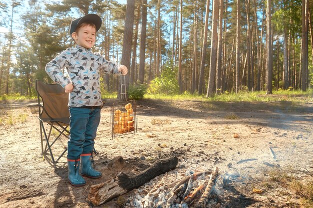 Un niño sostiene pepitas a la parrilla junto al fuego.