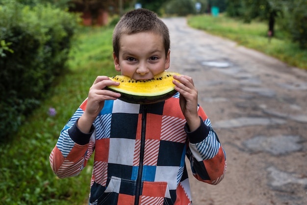 Foto un niño sostiene una sandía amarilla y quiere comérsela.