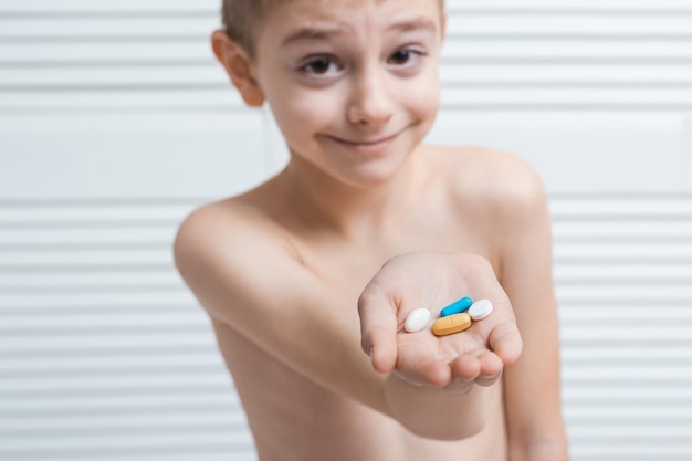 Niño sostiene tableta en la palma y sonríe Vitaminas para la salud de los niños para niños