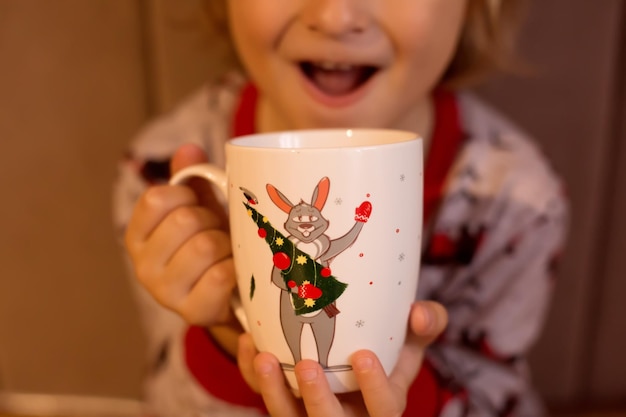 un niño sostiene una taza blanca con el símbolo de Año Nuevo el año del conejo en sus manos