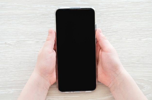 El niño sostiene un teléfono. Manos con el teléfono.