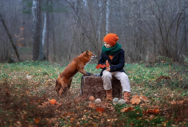 El niño y su amigo el zorro en el bosque de otoño