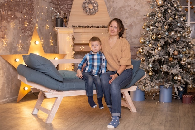 Niño y su madre en casa cerca de la chimenea y el árbol de Navidad.