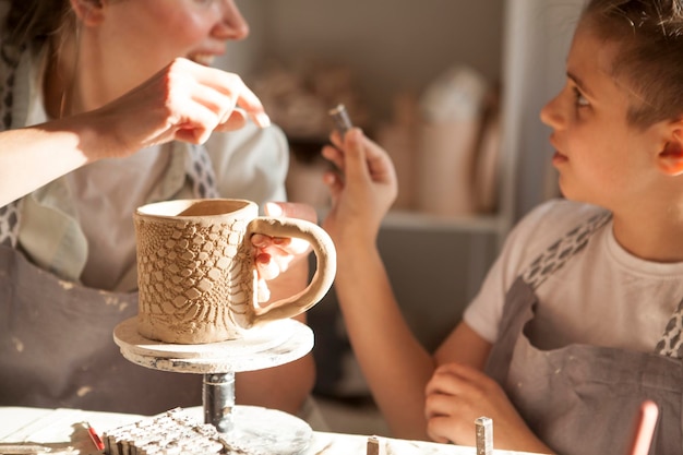 El niño y su madre decoran una taza de cerámica hecha a mano