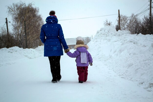 El niño y su madre, tomados de la mano, salieron a pasear en invierno.