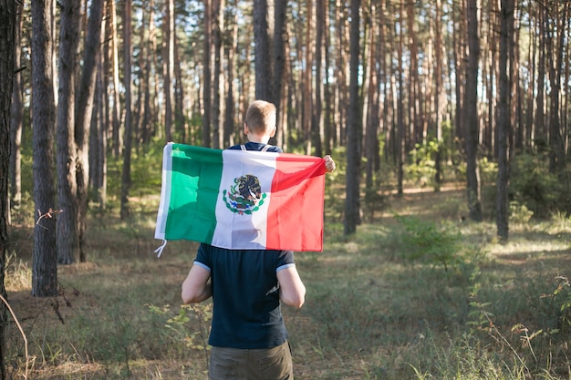 Foto niño con su padre sosteniendo la bandera mexicana
