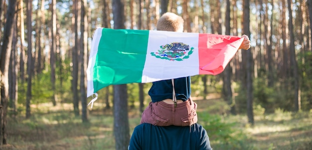 Niño con su padre sosteniendo la bandera mexicana