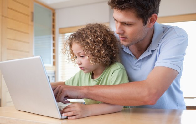 Niño y su padre usando una computadora portátil