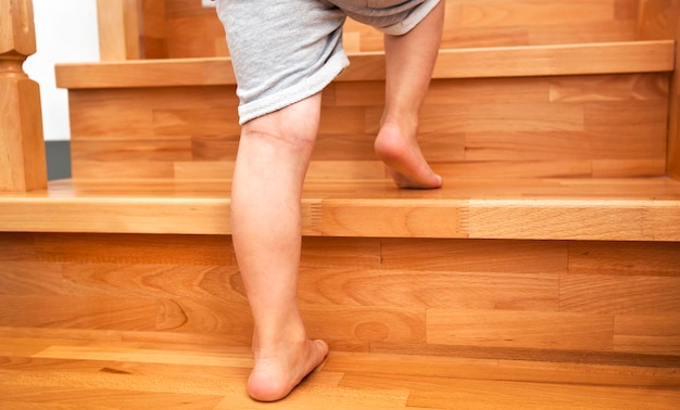 El niño sube por las escaleras de madera en casa.