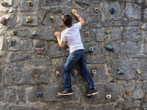 Foto el niño se sube a la pared.