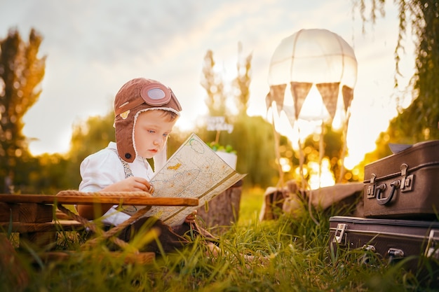 Un niño sueña con convertirse en piloto mirando un mapa al aire libre