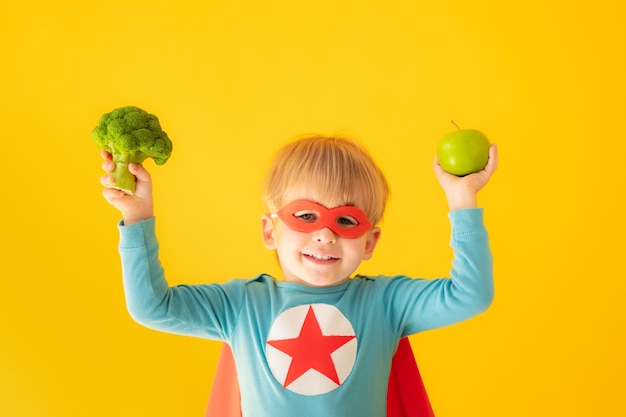 Niño superhéroe con brócoli y manzana