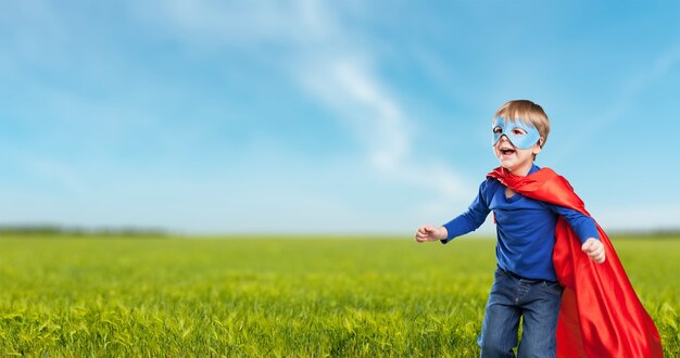 Niño superhéroe contra el espectacular fondo de cielo azul