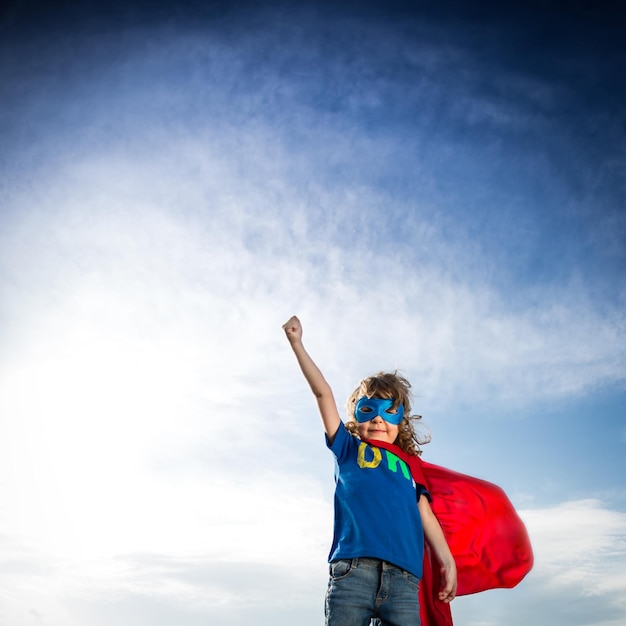 Foto niño superhéroe contra el fondo de cielo azul dramático