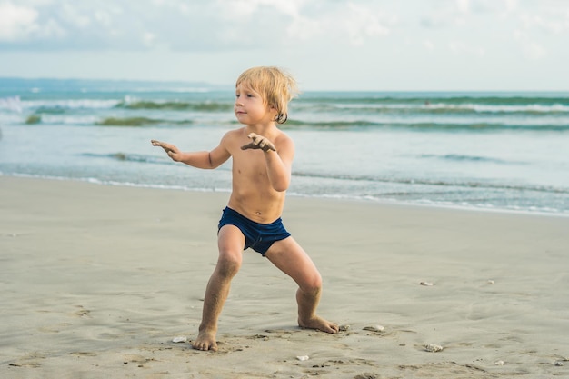 Niño surfeando en una playa tropical. Niño en tabla de surf en ola oceánica. Deportes acuáticos activos para niños. Niño nadando con surf. Lección de surf para niños.