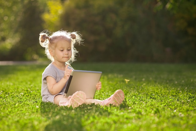 Niño con una tableta sentado en el parque