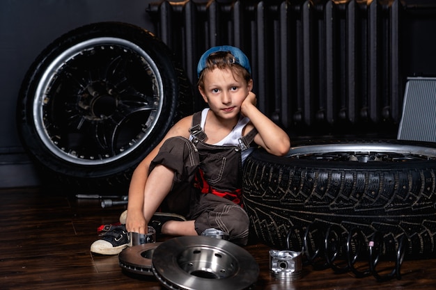 Foto un niño en un taller de reparación de automóviles entre las ruedas y las piezas del automóvil