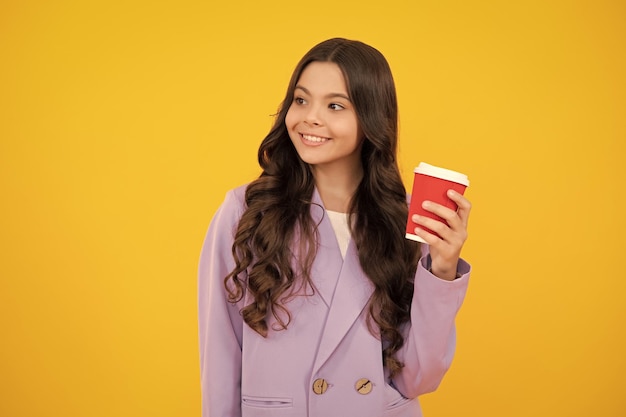 Niño con taza de café o té aislado sobre fondo de estudio amarillo Adolescente con bebida para llevar Cara feliz emociones positivas y sonrientes de niña adolescente