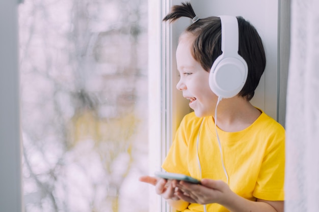 Un niño con un teléfono está sentado en una ventana de estilo de vida. Redes sociales. Niños modernos. Un artículo sobre niños desarrollados. Tecnologías modernas