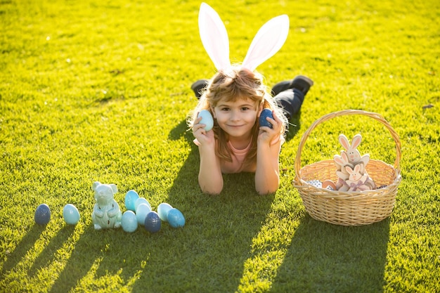 Niño tendido en la hierba en el parque con huevos de pascua