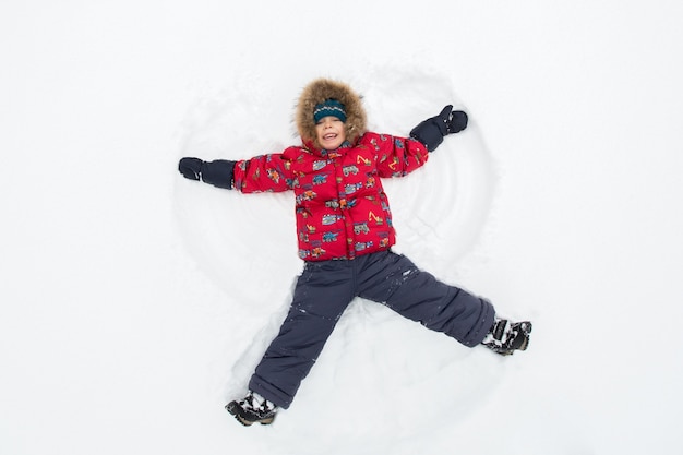 Niño tendido en la nieve haciendo un ángel de nieve