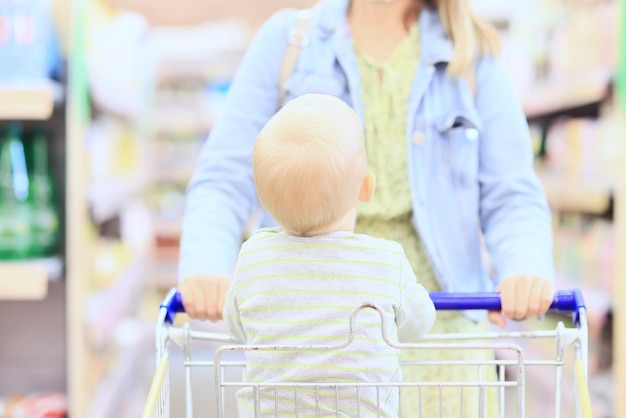 niño en la tienda en el carrito de la compra es un pequeño cliente