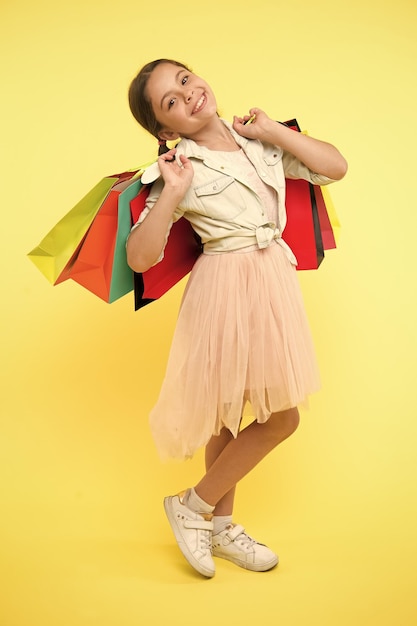 Niño en la tienda niño feliz en la tienda con bolsas niña hermosa niña en la tienda concepto de tienda para niños ir de compras es la mejor terapia