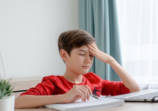 Un niño tiene dolor de cabeza por estudiar el concepto de educación en casa.
