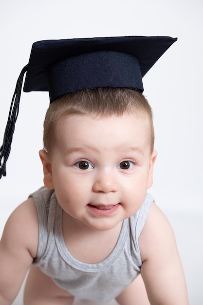 Un niño tiene una gorra negra de graduación con una borla en un fondo blanco aislado Úselo para un concepto escolar o educativo