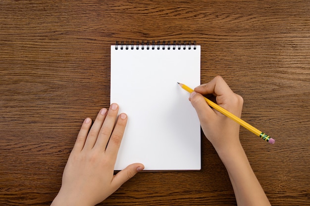 Foto niño tiene lápiz en mano y escribe en un cuaderno