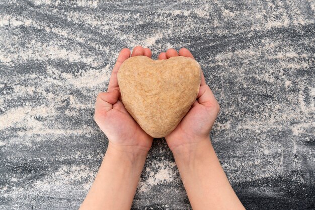 El niño tiene una masa en forma de corazón. Galletas caseras con amor.