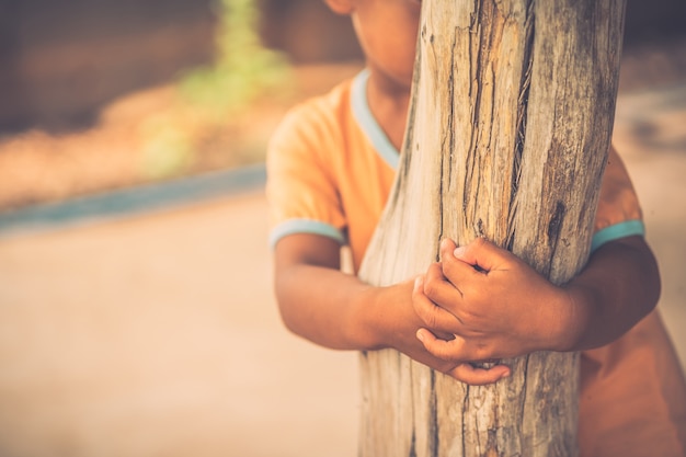 Niño tímido que está de pie detrás de los pilares