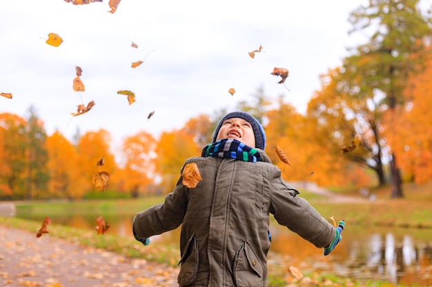 El niño tira hojas de otoño Artículo de otoño Un niño feliz Otoño