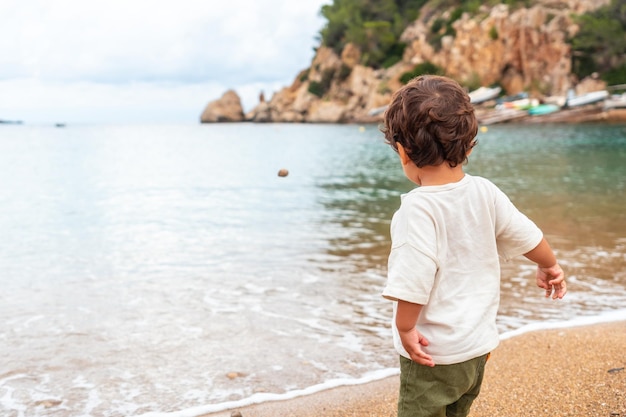 Un niño tirando piedras en la playa del puerto de Sant Miquel Ibiza Isla Islas Baleares