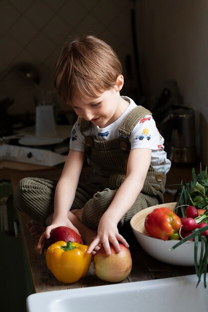 Foto niño de tiro completo con frutas y verduras